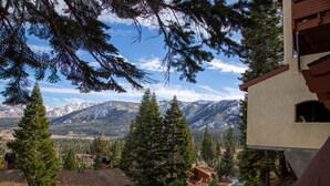Un chalet de montagne avec des cabanes en bois, une terrasse et une vue sur les montagnes enneigées.