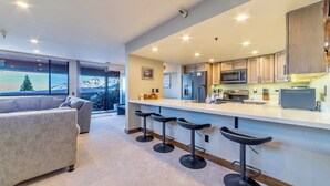 Une cuisine moderne avec un coin bar, de grandes fenêtres et une vue sur les montagnes.