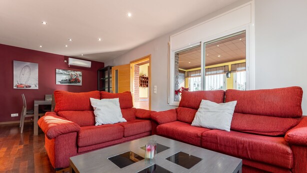 A modern living room with red upholstered sofas, a glass-top coffee table, and a dining area with a chair and table. - Chalet 'Casa Thaiker' with Mountain Views, Garden, BBQ & A/C (Miami playa.  Tarragona)