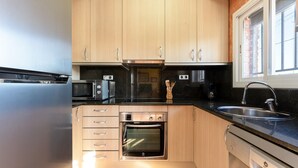 A modern kitchen with wooden cabinets, a built-in oven, a microwave, a coffee maker, and a sink. - Chalet 'Casa Thaiker' with Mountain Views, Garden, BBQ & A/C (Miami playa.  Tarragona)