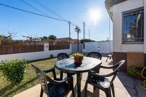 Un patio con una mesa redonda y sillas, una planta en maceta y vistas a una zona residencial.