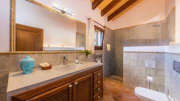 Een badkamer met een houten wastafelmeubel, een grote spiegel, een douche en een toilet.