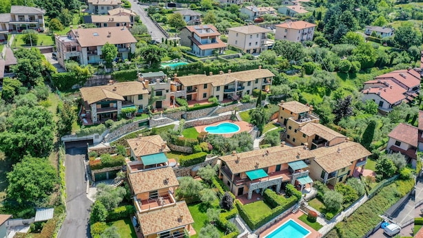 An aerial view of a residential area with multiple two-story houses, a swimming pool, and well-maintained gardens.