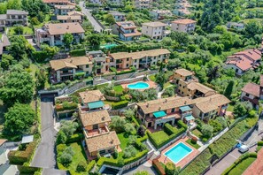 An aerial view of a residential area with multiple two-story houses, a swimming pool, and well-maintained gardens. - Cosy Apartment "Gardasee Castion" with Garden, Shared Pool, A/C & Wi-Fi (Castion)