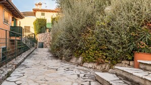A stone-paved pathway leading to a building with a stone wall and a metal fence.
