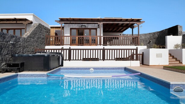 A modern pool area with a hot tub, a wooden deck, and a stone wall. - Villa Peaky with Sea & Mountain View, Pool & Sauna (Yazia)