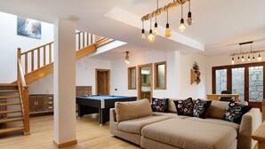 A spacious living area with a pool table, a sofa, a staircase, and a dining area. - Villa Peaky with Sea & Mountain View, Pool & Sauna (Yazia)