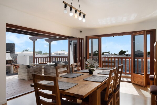 An open-plan dining area with a wooden table, chairs, and a view of the outdoors.