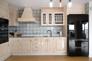 A kitchen with wooden cabinets, a black refrigerator, and a tiled backsplash.