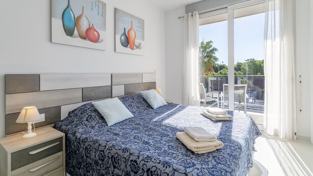 Une chambre à coucher avec un lit, une table de chevet et une vue sur l’extérieur.