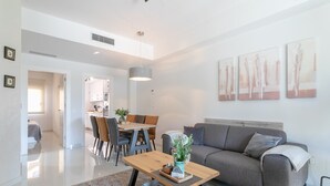 Un salon moderne comprenant un canapé, une table basse et un coin repas avec des chaises et une table.