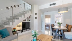 Un salon moderne avec un escalier, un coin repas et un téléviseur.