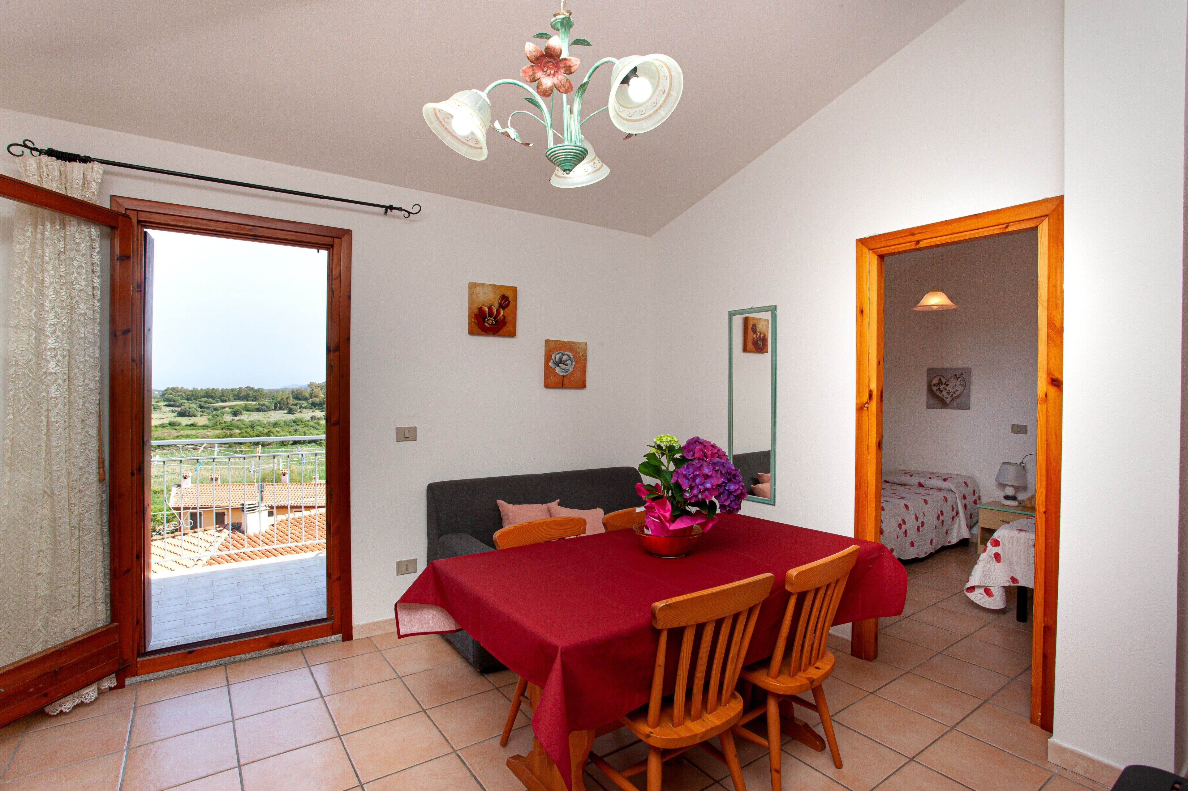 Uma sala de jantar com mesa posta para quatro pessoas, um sofá e uma varanda com vista.