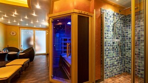 Un cuarto de spa con sauna, una camilla de masaje y una zona de estar con sillas.