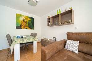 Ein Essbereich mit Tisch, Stühlen, einer Couch und einem Wandregal mit Dekoration.