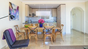 Una cocina moderna con armarios de madera, una mesa de comedor con sillas y una lámpara colgante.