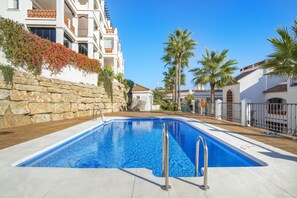 Una piscina con muro de piedra y palmeras.