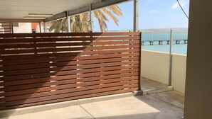 Un espacio al aire libre techado con piso de concreto, cerca de madera y vista a un cuerpo de agua y un puente.