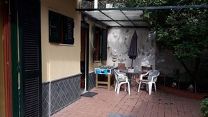 Zona de terrassa amb taula de futbolí, dues cadires de plàstic blanc i una taula petita i rodona.