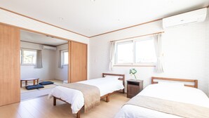 A hotel room with two beds, a small table, and a window with curtains. - SEASIDE HOUSE YASUTAKETEI (Shirahama)