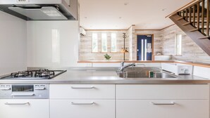 A modern kitchen with a gas stove, built-in oven, and stainless steel sink. - SEASIDE HOUSE YASUTAKETEI (Shirahama)