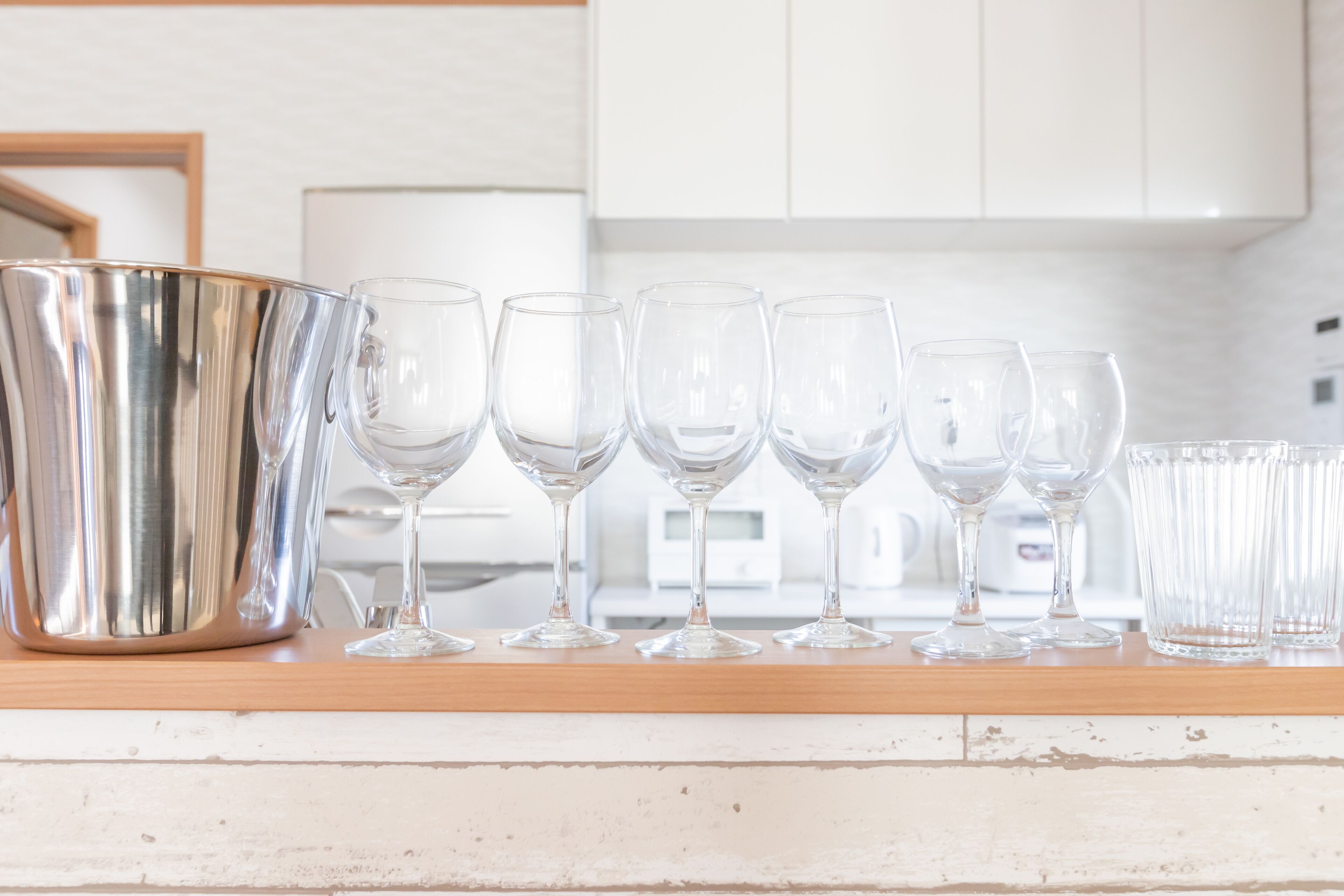 Un comptoir de cuisine sur lequel sont posés une casserole en acier inoxydable et six verres à vin alignés.
