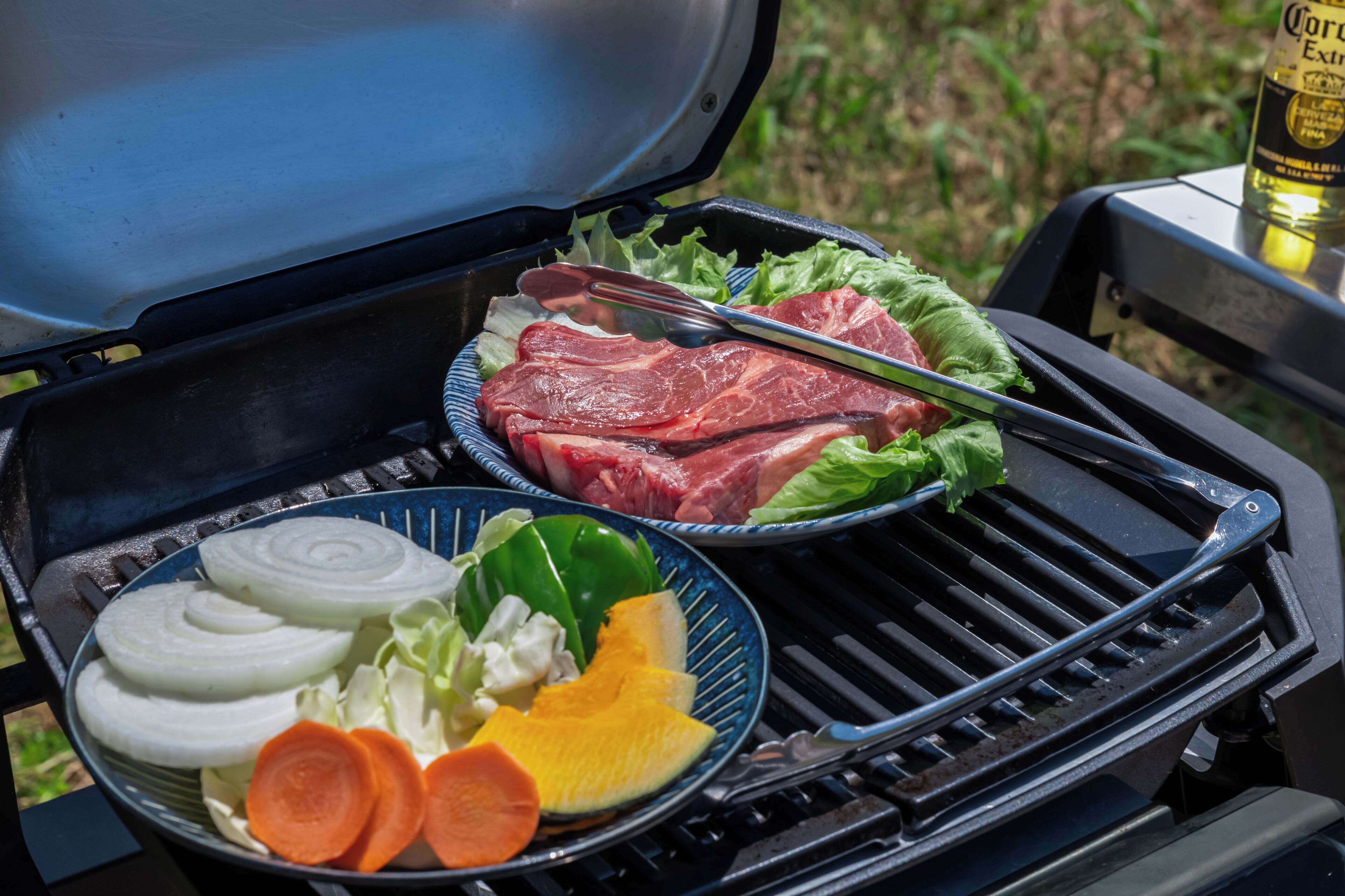 Een barbecue met rauw vlees en groenten.