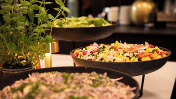 A buffet with various dishes, including salads and a plant.
