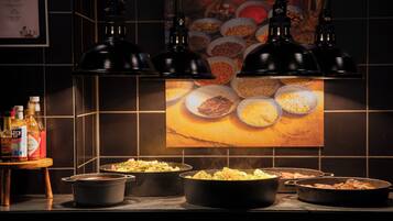 A kitchen counter with various cooking pots and pans, a wooden table with condiments, and a tiled backsplash with a poster.