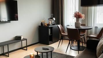 Una sala de estar moderna con un televisor de pantalla plana, una cafetera, una mesita con una vela y un sofá.