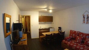 Ett kompakt bostadsutrymme med ett litet kök, en matplats och en soffa.