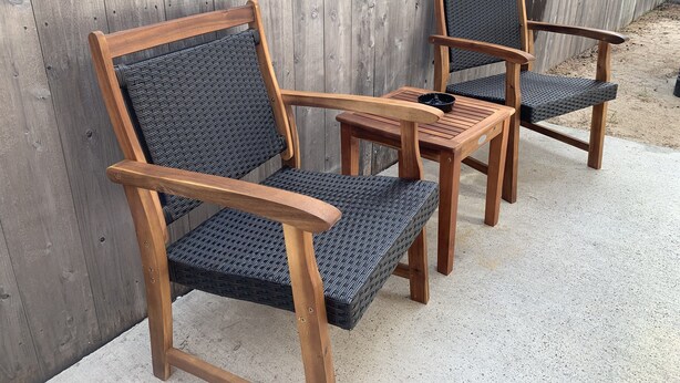 Vier Holzstühle mit geflochtenen Sitzflächen und Rückenlehnen sind um einen kleinen Holztisch gestellt.