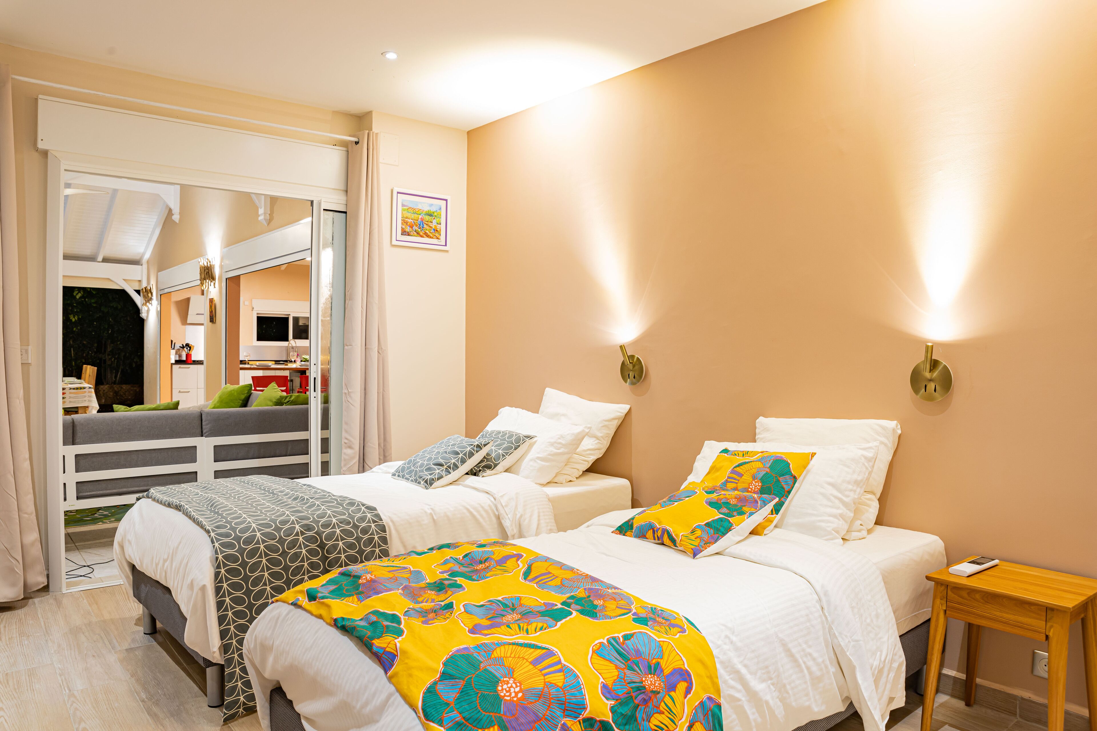 A hotel room with two beds, a wooden nightstand, and a view of the outside.