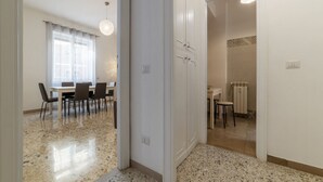 Ein Zimmer mit Esstisch, Stühlen, einer Küchenzeile und einer Tür zu einem weiteren Raum.