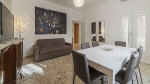 Ein modernes Wohnzimmer mit einem weißen Tisch, einem grauen Sofa und einem großen abstrakten Gemälde an der Wand.