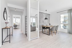 Een moderne, open woonruimte met een eethoek, een grote spiegel en uitzicht op de stad door een raam.