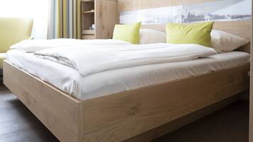 Una cama de madera con ropa de cama blanca y almohadas verdes en una habitación de hotel.