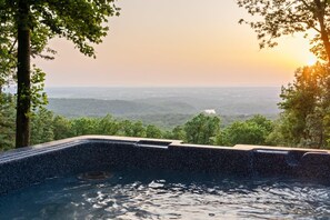 Un jacuzzi con vistas a un paisaje boscoso al atardecer.