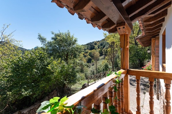 Ein hölzerner Balkon mit Blick auf eine üppige grüne Landschaft und Hügel.