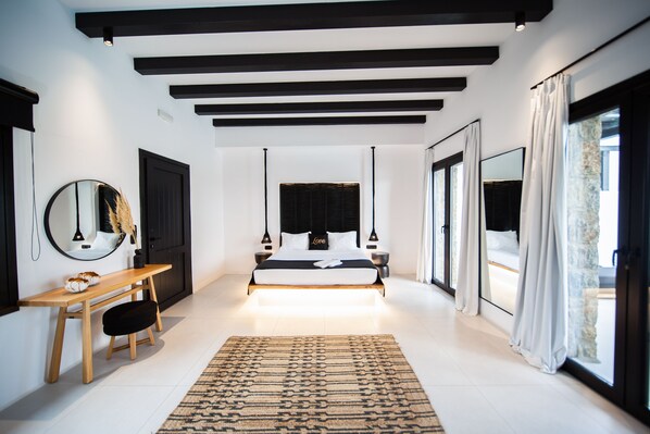 Un dormitorio moderno con una cama grande, mesitas de noche, un escritorio y un espejo.