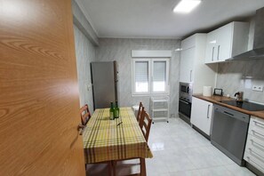 A kitchen with a dining table, chairs, a refrigerator, a microwave, a stove, and a dishwasher.