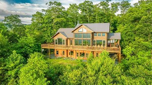 A large wooden house with multiple decks, surrounded by dense greenery. - Experience breathtaking mountain views at Sequoyah Sunset (Bryson City)