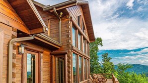 A wooden cabin with a deck, large windows, and a chimney. - Experience breathtaking mountain views at Sequoyah Sunset (Bryson City)