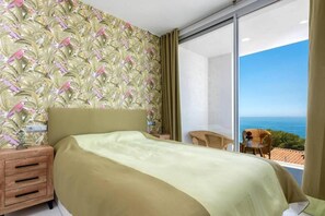 Une chambre à coucher avec un lit, une table de chevet, une chaise et une vue sur la mer.