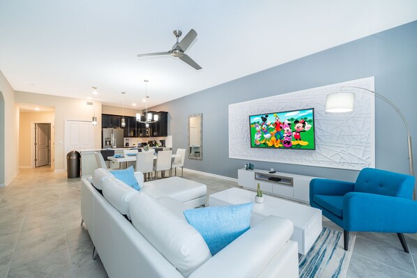 A modern living room with a white sofa, blue armchairs, and a flat-screen TV mounted on the wall. - FR1135 Champions Gate Condo 2Bedrooms 2Bathrooms Free Waterpark (Kissimmee)