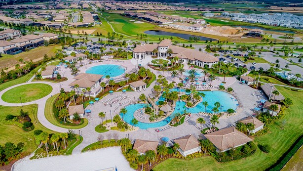 Vista aérea de um resort com várias piscinas, campo de golfe e edifícios residenciais.