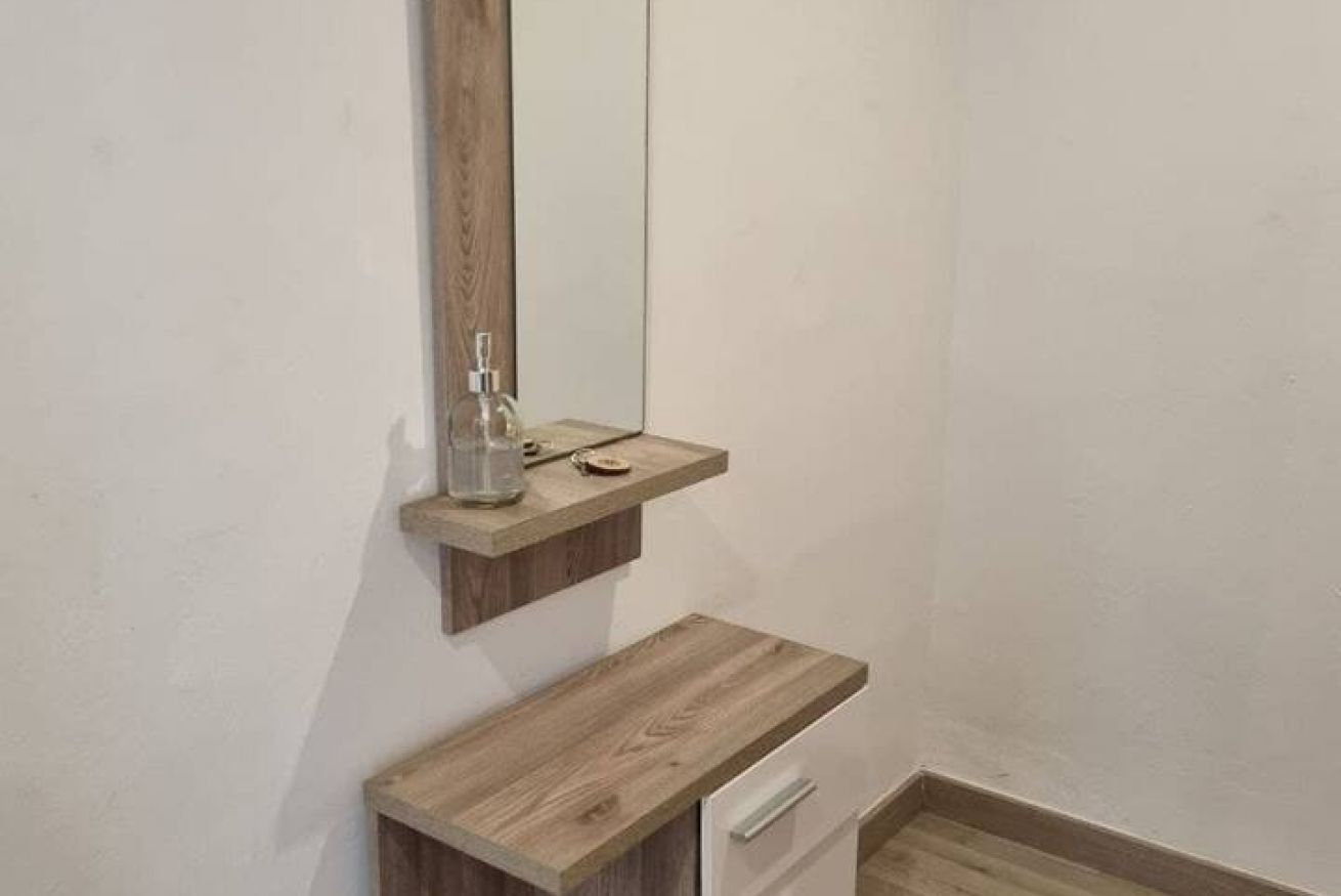Un bany amb un tocador de fusta, un mirall i un dispensador de sabó.