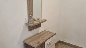 A bathroom with a wooden vanity, a mirror, and a soap dispenser. - 103A By R2R 2-Bedroom Apartment (Gijón)