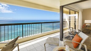 A balcony with a view of the ocean, a table with chairs, and a glass of drink. - Amazing OCEAN VIEWS, Full Kitchen, Washer/Dryer, Pool, Newly Renovated 2018 (Honolulu)
