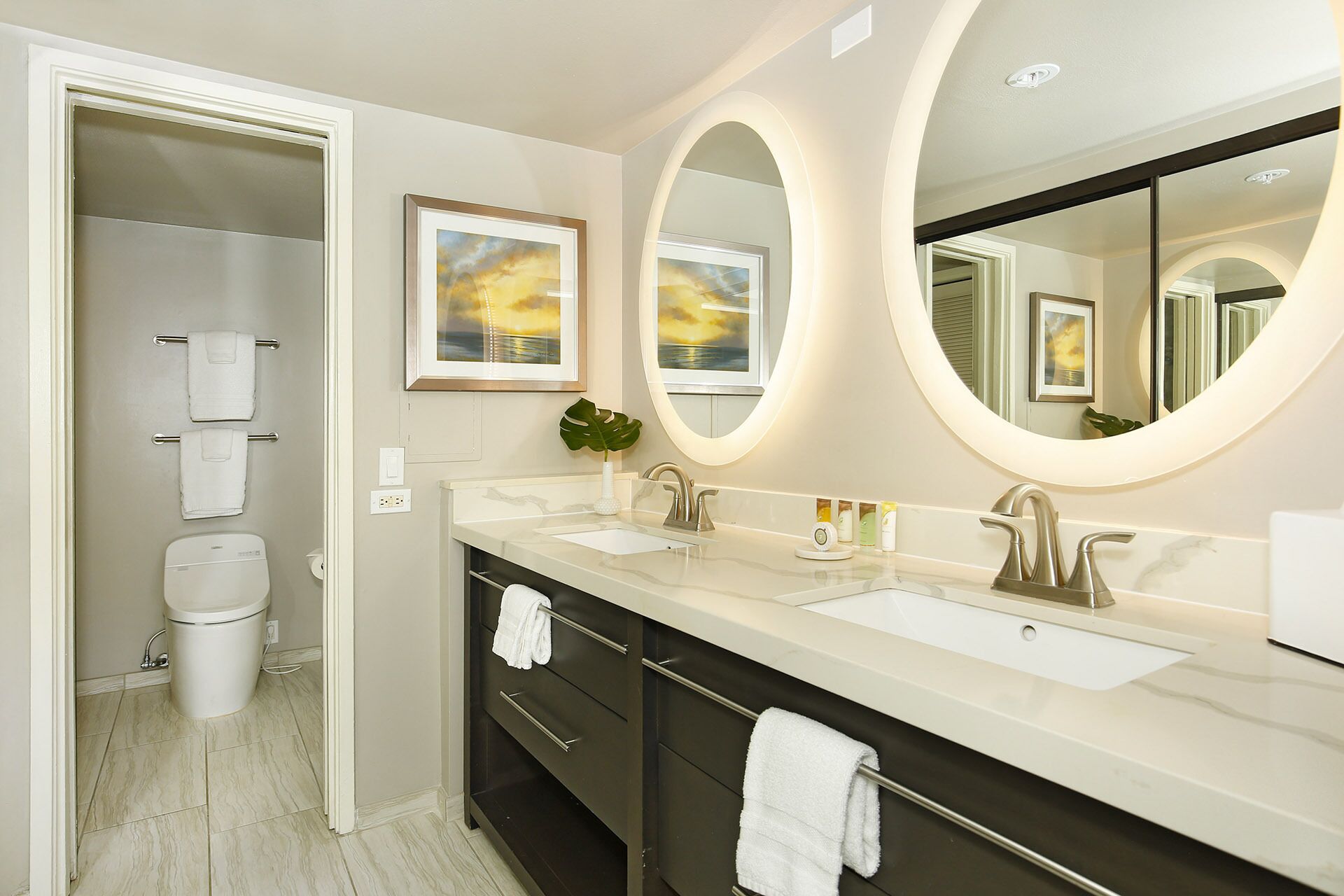 A modern bathroom with two sinks, a large mirror, and a toilet.